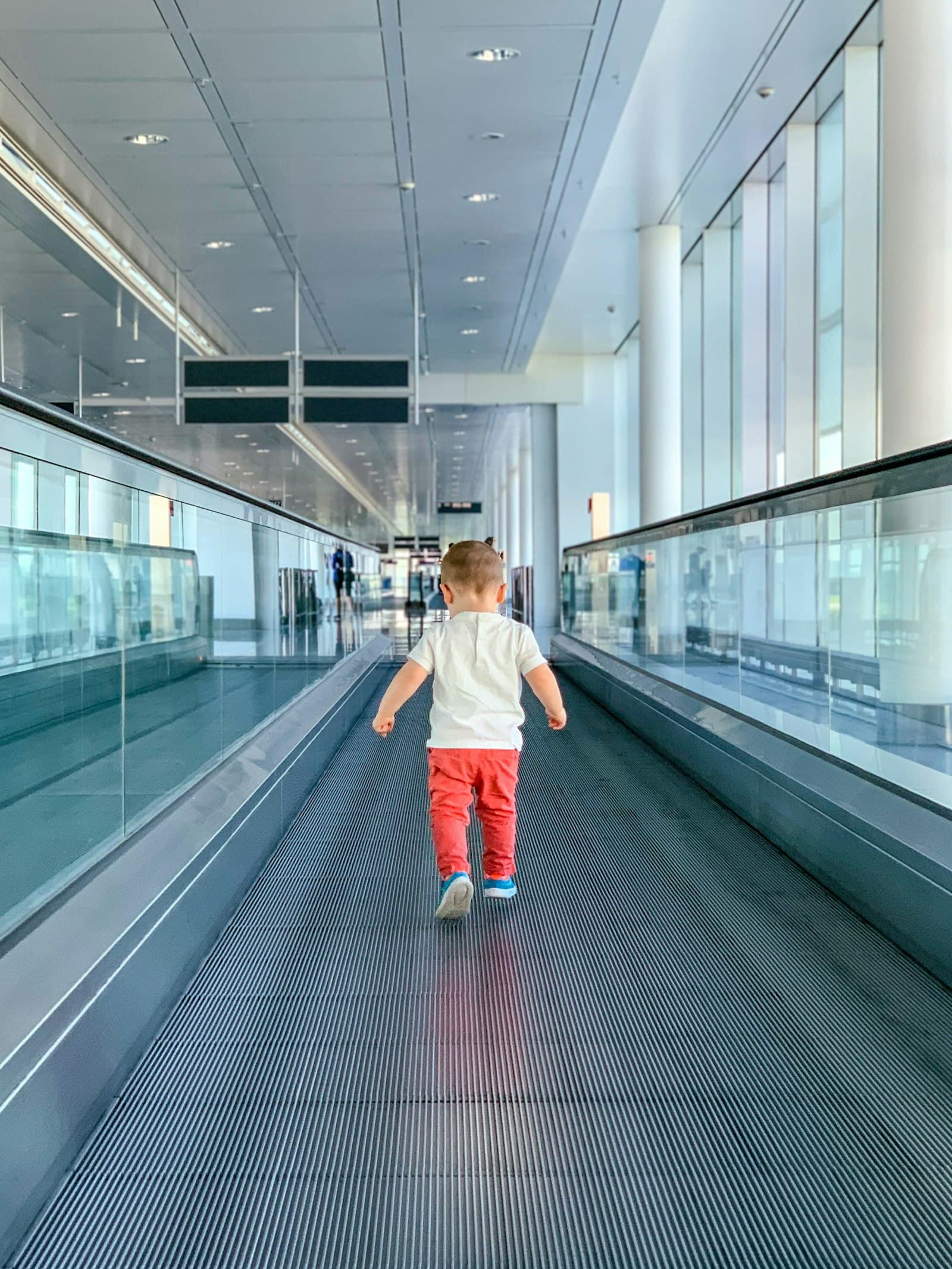 Peuter loopt zelfstandig over de rolbaan in een lichte terminal